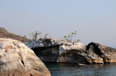 Kaya kayaları ve bazı ağaçlar Malawi Gölü 'nün kenarında bir sanat eseri oluşturuyorlar.
