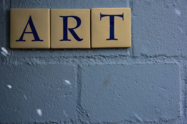 A blue backdrop wall with the word ART spelled out in tiles on it is begging for a story