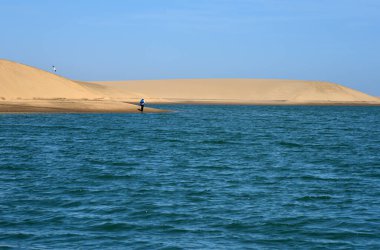 Namib Çölü 'nün kıyısındaki gölün etrafında dolaşan yalnız bir yürüyüşçü.