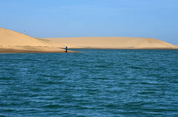 Namib Çölü 'nün kıyısındaki gölün etrafında dolaşan yalnız bir yürüyüşçü.