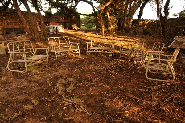 A ring of bamboo furniture set up in the middle of a junk yard