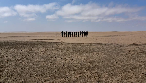 Bir grup yürüyüşçü Namib Çölü 'ndeki taşlaşmış bir kum tepesinden yaklaşıyor.
