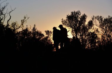 Doğu Burnu 'ndaki Karoo kasabası Graaff-Reinet yakınlarındaki Issız Vadi' de gün batımında tanınmayan insanlar.