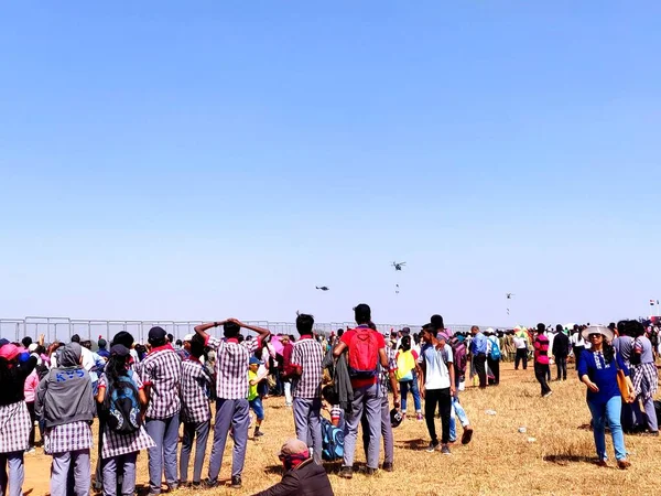 Okul öğrencilerinin bir hava gösterisini izlediği hevesli ve heyecanlı bir kalabalık.