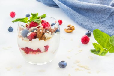 Sağlıklı yaban mersini, ahududu ve beyaz arka planda bir bardakta ceviz parfe.