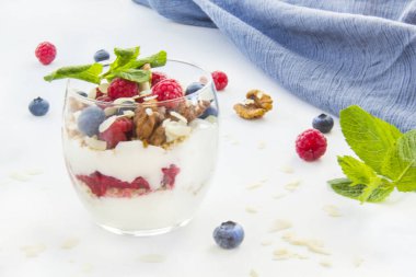 Sağlıklı yaban mersini, ahududu ve beyaz arka planda bir bardakta ceviz parfe.