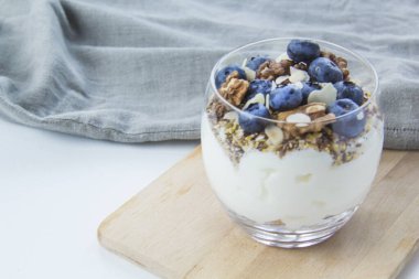 Sağlıklı yaban mersini ve beyaz arka planda bir bardakta cevizli parfe.