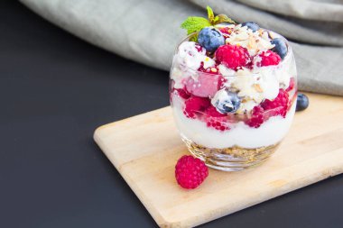 Sağlıklı yaban mersini, ahududu ve beyaz arka planda bir bardakta ceviz parfe.