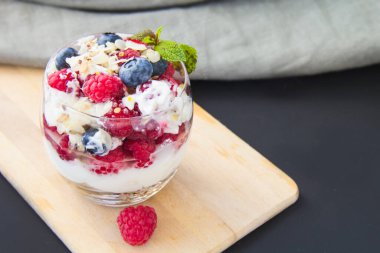 Sağlıklı yaban mersini, ahududu ve beyaz arka planda bir bardakta ceviz parfe.