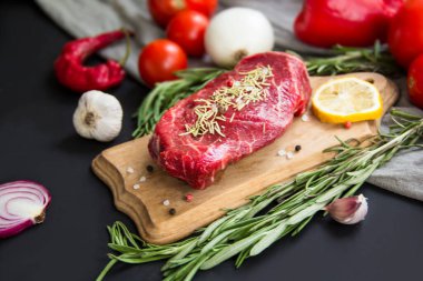 Kesme tahtasında baharatlı çiğ biftek. Yaratıcı atmosfer dekorasyonu.