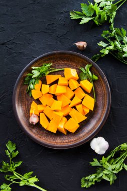 Çok güzel doğranmış balkabağı dilimleri, bitkiler ve yemek için malzemeler. Yaratıcı atmosfer dekorasyonu