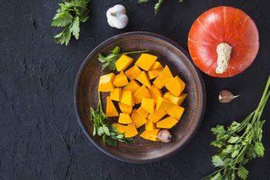 Çok güzel doğranmış balkabağı dilimleri, bitkiler ve yemek için malzemeler. Yaratıcı atmosfer dekorasyonu