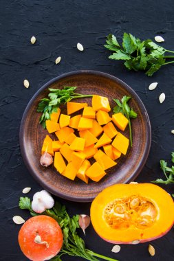 Çok güzel doğranmış balkabağı dilimleri, bitkiler ve yemek için malzemeler. Yaratıcı atmosfer dekorasyonu