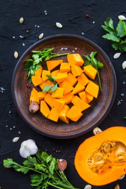 Çok güzel doğranmış balkabağı dilimleri, bitkiler ve yemek için malzemeler. Yaratıcı atmosfer dekorasyonu