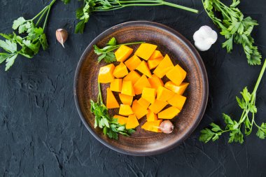 Çok güzel doğranmış balkabağı dilimleri, bitkiler ve yemek için malzemeler. Yaratıcı atmosfer dekorasyonu