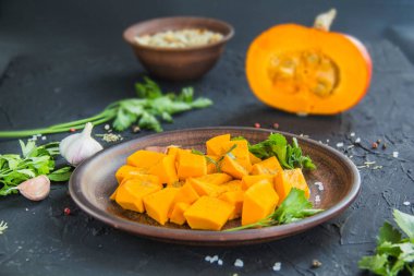 Çok güzel doğranmış balkabağı dilimleri, bitkiler ve yemek için malzemeler. Yaratıcı atmosfer dekorasyonu