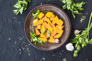Çok güzel doğranmış balkabağı dilimleri, bitkiler ve yemek için malzemeler. Yaratıcı atmosfer dekorasyonu