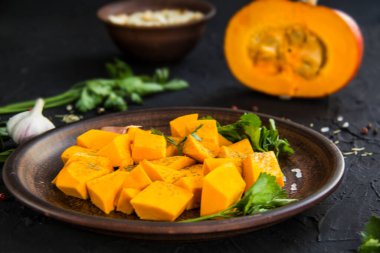 Çok güzel doğranmış balkabağı dilimleri, bitkiler ve yemek için malzemeler. Yaratıcı atmosfer dekorasyonu