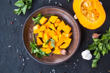 Çok güzel doğranmış balkabağı dilimleri, bitkiler ve yemek için malzemeler. Yaratıcı atmosfer dekorasyonu