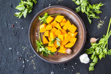 Çok güzel doğranmış balkabağı dilimleri, bitkiler ve yemek için malzemeler. Yaratıcı atmosfer dekorasyonu