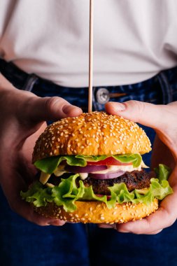 Elinde hamburger tutan bir kadın.