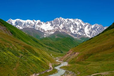 Georgia mı? Svaney 'de yaz günü. Inguri Nehri' nin kaynağına giden yol ve Shkhara Dağı. Ufukta Shkhara Dağı. Inguri nehri..
