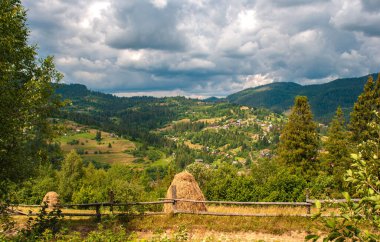 Karpatlar yaz gününde. Dağ manzarası. Vadideki köy. Haystack. Cumulus bulutları..