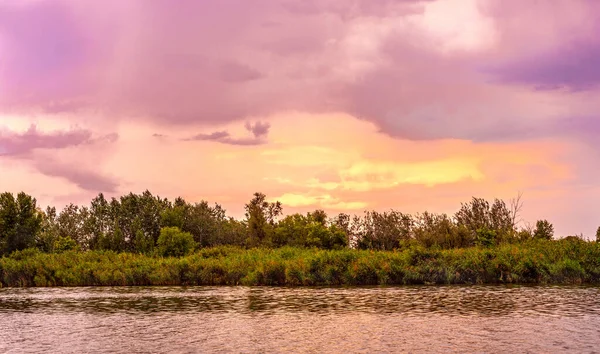 River bank.Purple sky with clouds.Yellow sun glare.