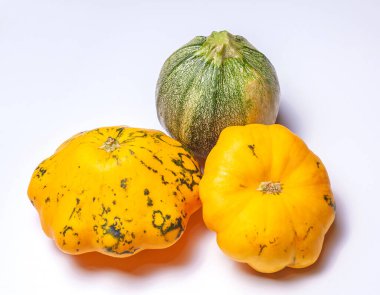 İki sarı patison ve bir kabak beyaz arka planda izole edilmiş. Olgun, taze meyveler. Kabakta yeşil noktalar..