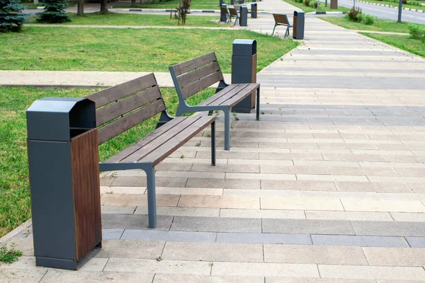 Close-up of brown benches and garbage bins. Arrangement of streets and parks for the rest outdoors, maintenance of the clean in urban public places. Saving environment, clean planet, ecology concept.