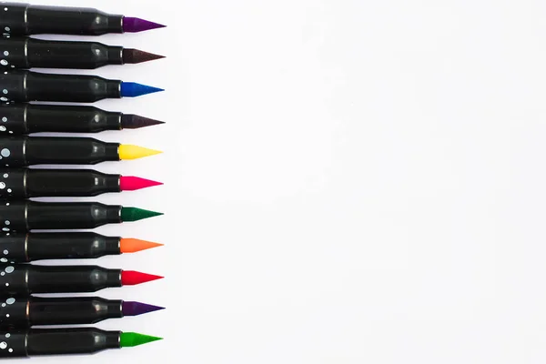 Multicolored watercolor markers for artist lie in a row on a white background. Flat lay. The material for the education and drawing. The concept of going back to school. Top view with copy space.