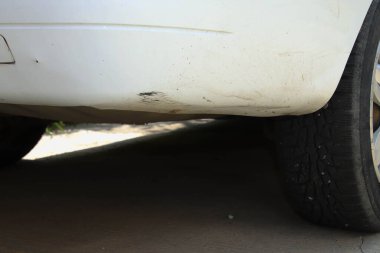 Eski, beyaz bir arabanın arka çubuğu çizilmiş..