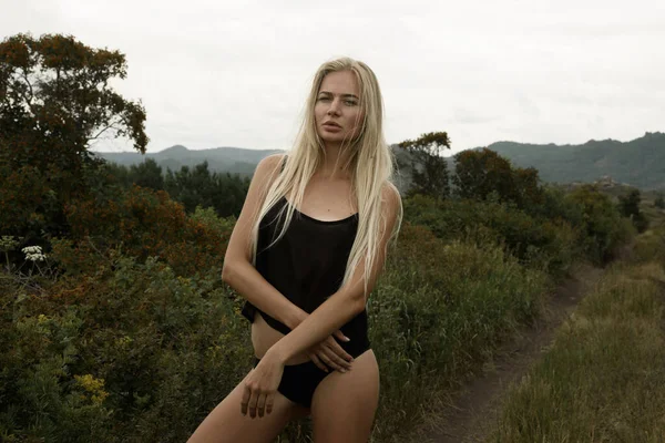 Stilvolles Mädchen in Schwarz posiert vor der Kulisse einer wilden Landschaft — Stockfoto
