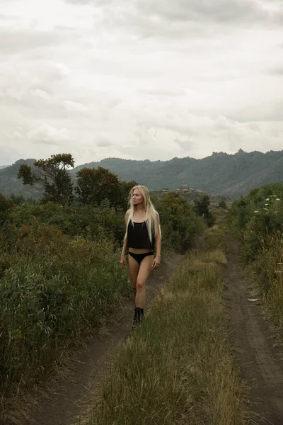 Siyah elbiseli şık bir kız güzel bir manzaranın arka planına karşı çıkıyor.