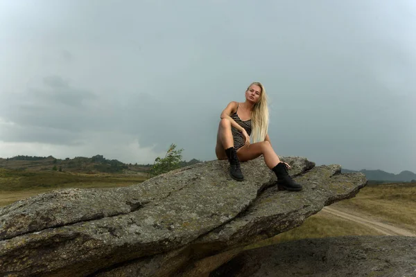 Kadın kayanın üzerinde oturuyor.