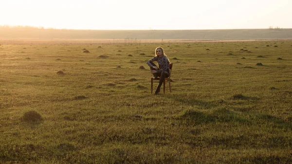 Yalnız kız tarlanın ortasında bir sandalyede oturuyor.
