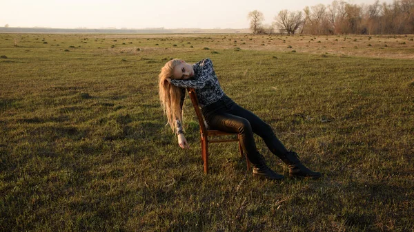 Samotna dziewczyna siedzi na krześle na środku pola — Zdjęcie stockowe