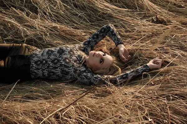 La ragazza è sdraiata sull'erba secca. Uno sguardo alla telecamera. — Foto Stock