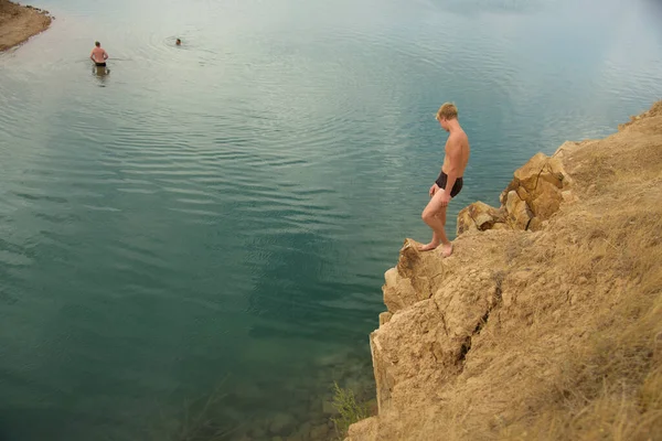Έφηβος σε βραχώδη ακτή πριν κολυμπήσει σε μπλε, καθαρή λίμνη — Φωτογραφία Αρχείου