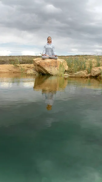 Jong meisje doet yoga op het meer met helder water — Stockfoto