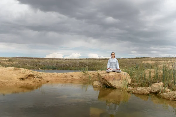 Jong meisje doet yoga op het meer met helder water — Stockfoto