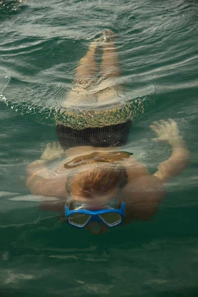 Adam bir maskeyle suyun altında yüzüyor.