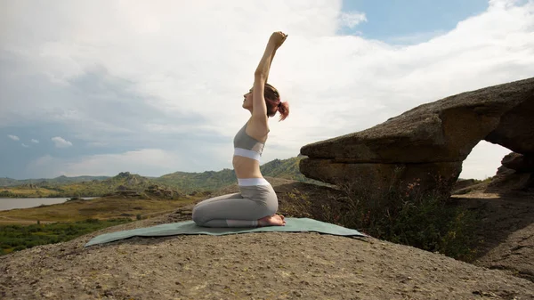 Büyük taşlarla yoga yapan genç bir kadın..
