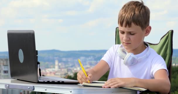 Мальчик Записывает Данные Блокнот Надевает Наушники Работает Ноутбуке — стоковое видео
