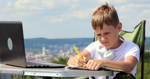 男孩坐在笔记本电脑前 在笔记本上写着数据 然后看着一台单眼望远镜 — 图库视频影像
