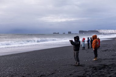 İnsanlar manzaranın ve Reynisfjara Choni sahilindeki Atlantik Okyanusu 'nun dalgalarının fotoğraflarını çeker.