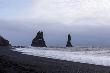 Reynisfjara kara plajı ve kayalar kışın Atlantik Okyanusu 'ndan yükseliyor.