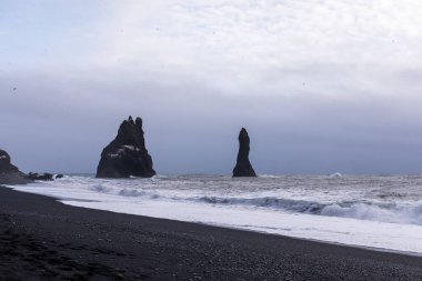 Reynisfjara kara plajı ve kayalar kışın Atlantik Okyanusu 'ndan yükseliyor.