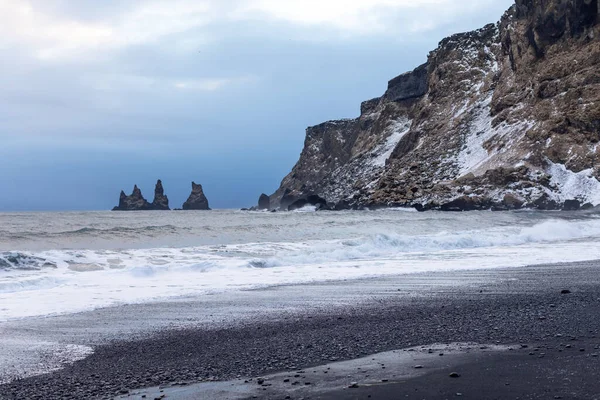 Siyah sahil, kayalar ve Vik Reynisdrangar yakınlarındaki dalgalar kış günbatımında