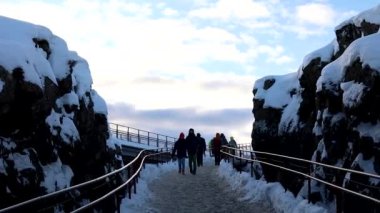 Genç çift, Kontinental Spalte kayası ve Oxararfoss yakınlarındaki Küçük İzlanda Nehri 'ni takip ederek Thingvellir Ulusal Parkı' ndaki donmuş şelaleyi izliyor.